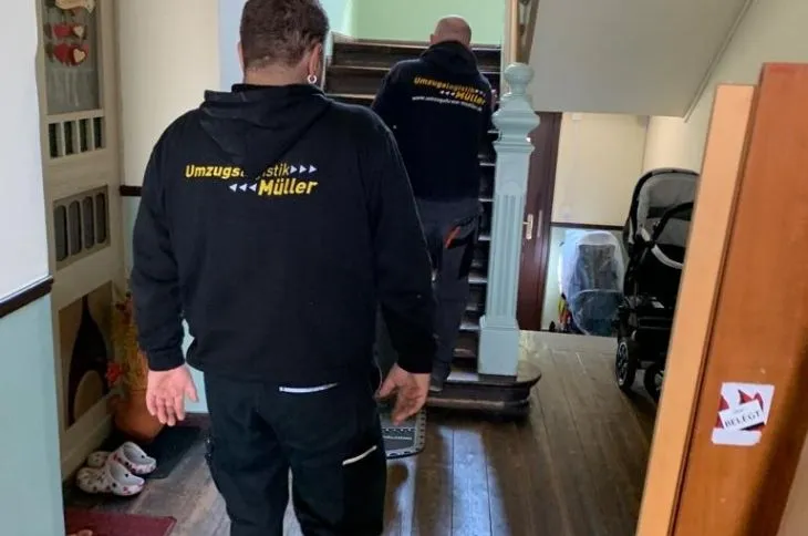 zwei umzugshelfer gehen durch treppenhaus beim umzug